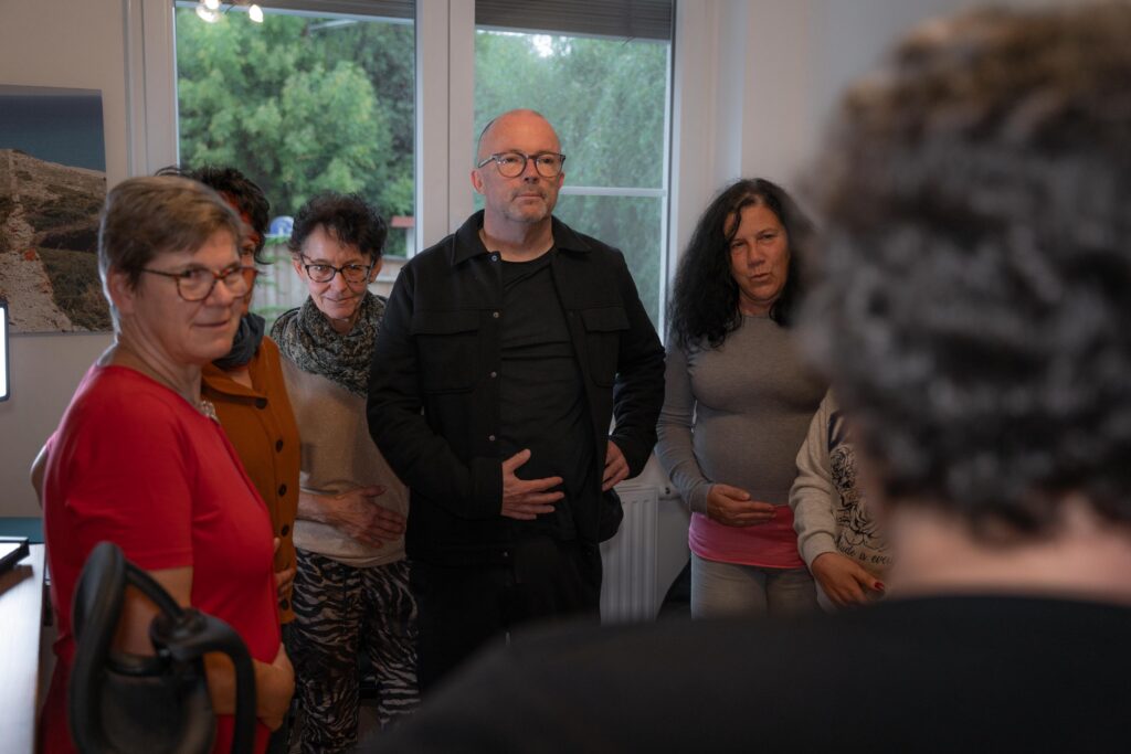 Abbildung zeigt mehrere Personen, die von Dani Grießbauer zu einer Atemübung angeleitet werden